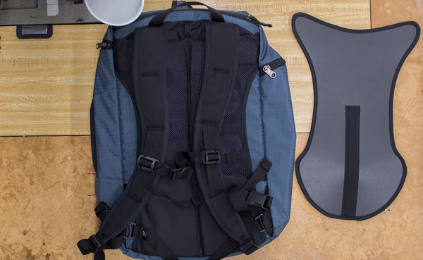 The optional Techonaut Internal Frame next to a Techonaut 30 in Night Walk 400d; both are on a sewing machine table in the TOM BIHN factory.
